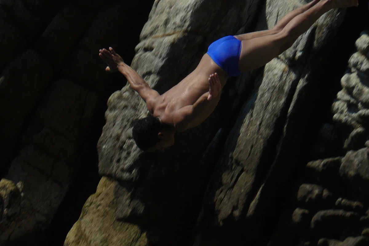 A La Quebrada cliff diver mid-dive against the rock face