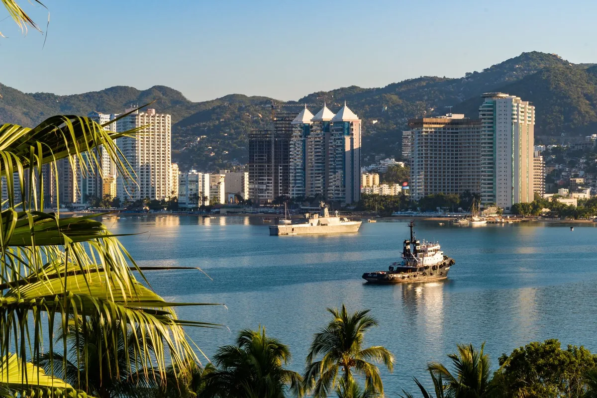 Acapulco Bay and the Costera high-rises in morning light, with a tug and a naval vessel on the water