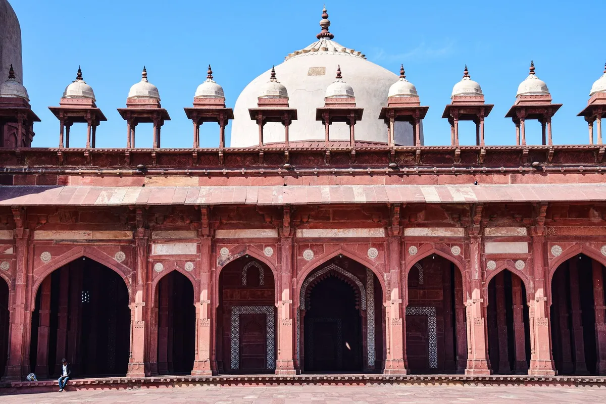 The red sandstone Jama Masjid courtyard at Fatehpur Sikri, with the white marble tomb of Salim Chishti behind