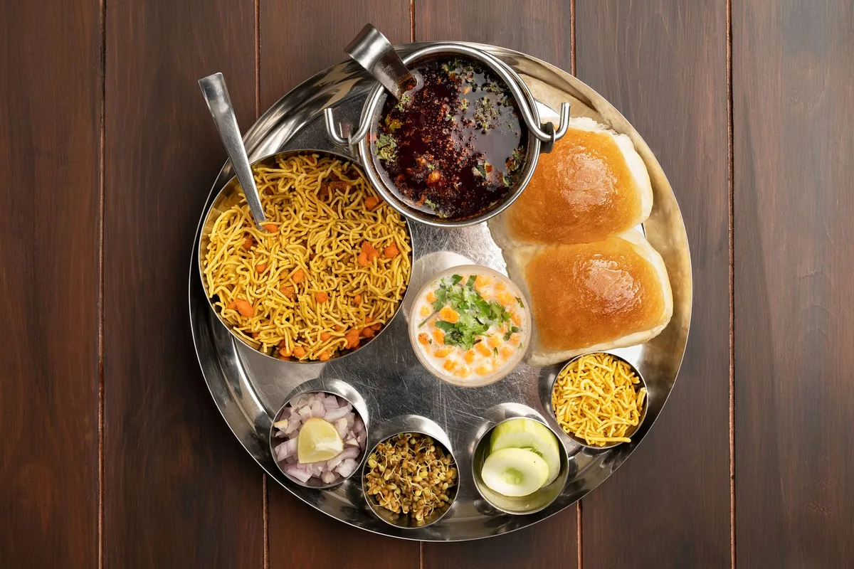 A steel thali of curries, rice, breads and chutneys seen from above