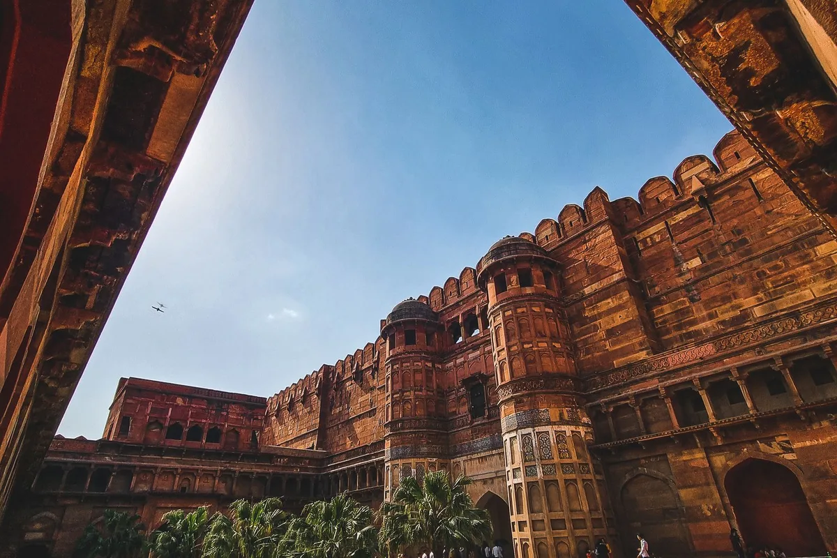 Agra Fort's red sandstone walls and lawns seen through a carved archway