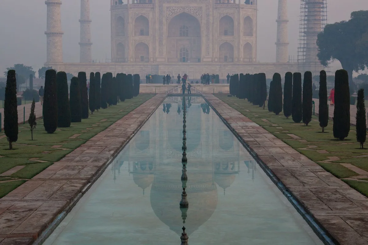 The Taj Mahal in winter morning mist at the end of the reflecting pool