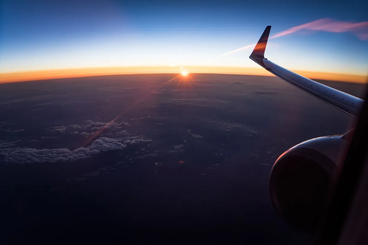 An aircraft wing above the clouds at sunrise, on the flight into Geneva