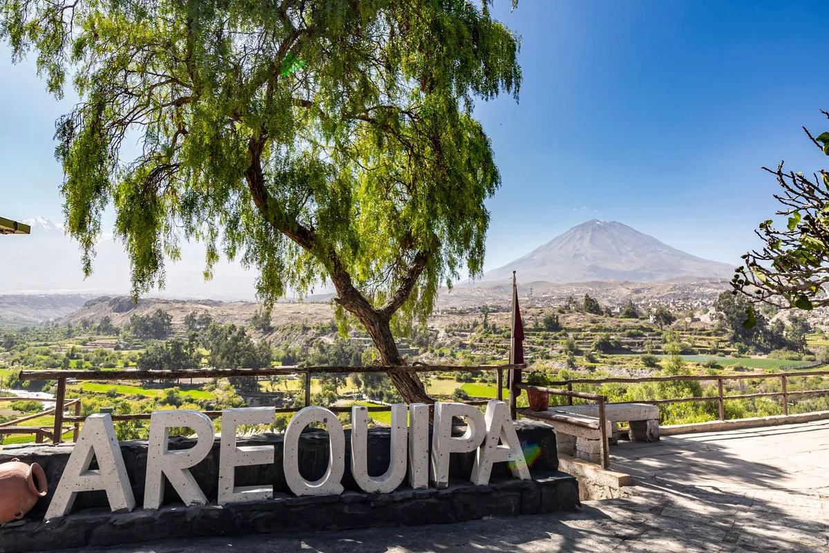 A viewpoint sign spelling Arequipa with El Misti volcano on the horizon
