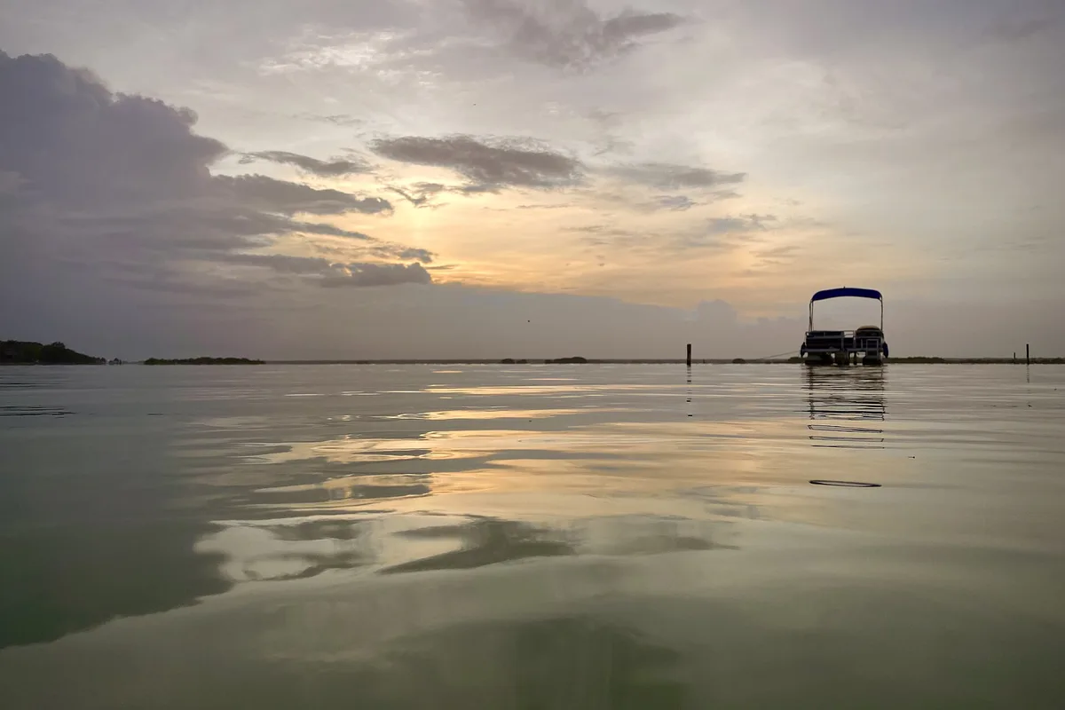 Dawn over the glassy lagoon, a tour boat silhouetted on still water