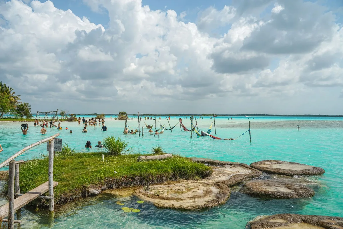 Bathers in the lagoon shallows, where pale stromatolite discs dot the sandy floor