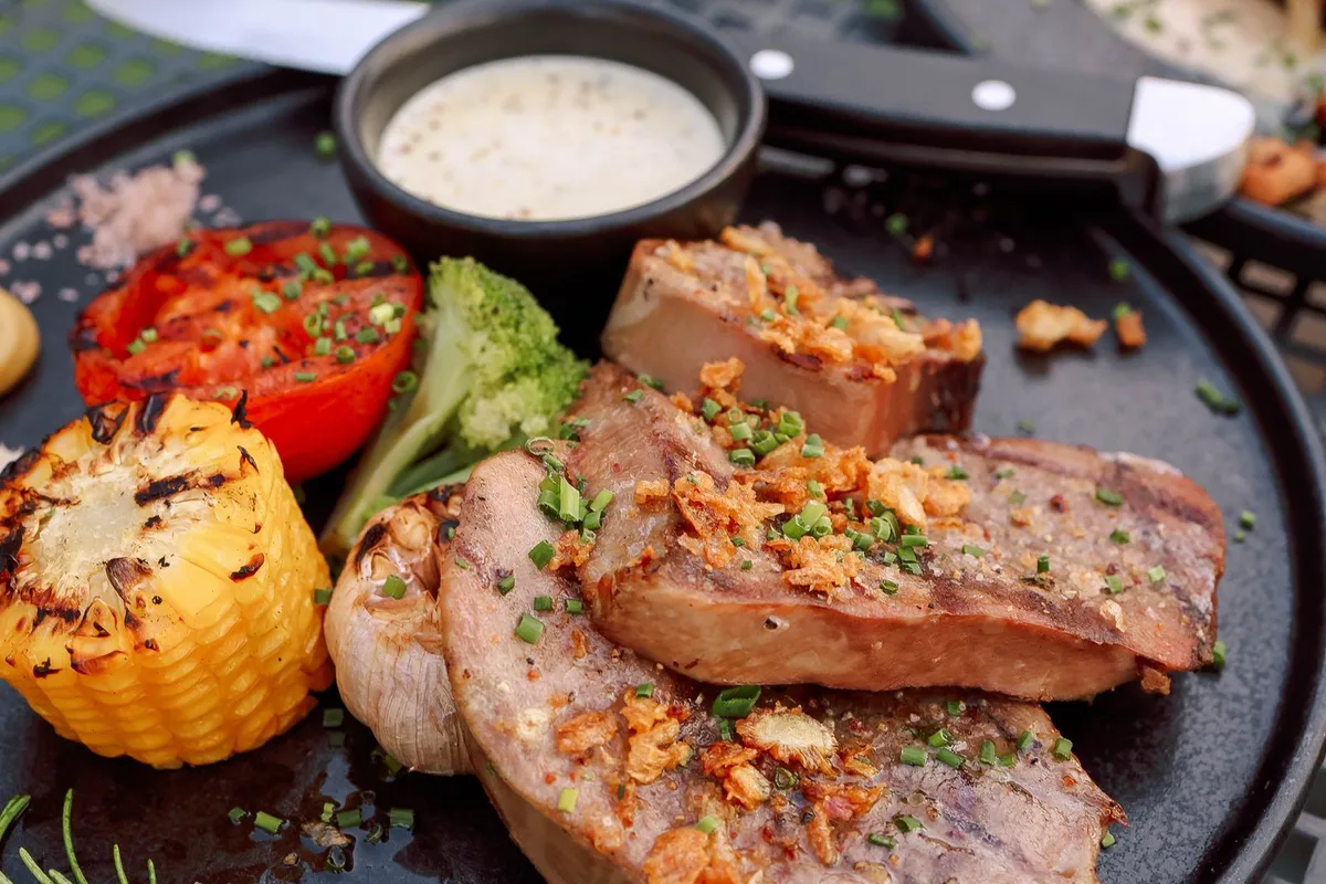 Grilled steaks with roasted tomatoes and vegetables on a sharing board
