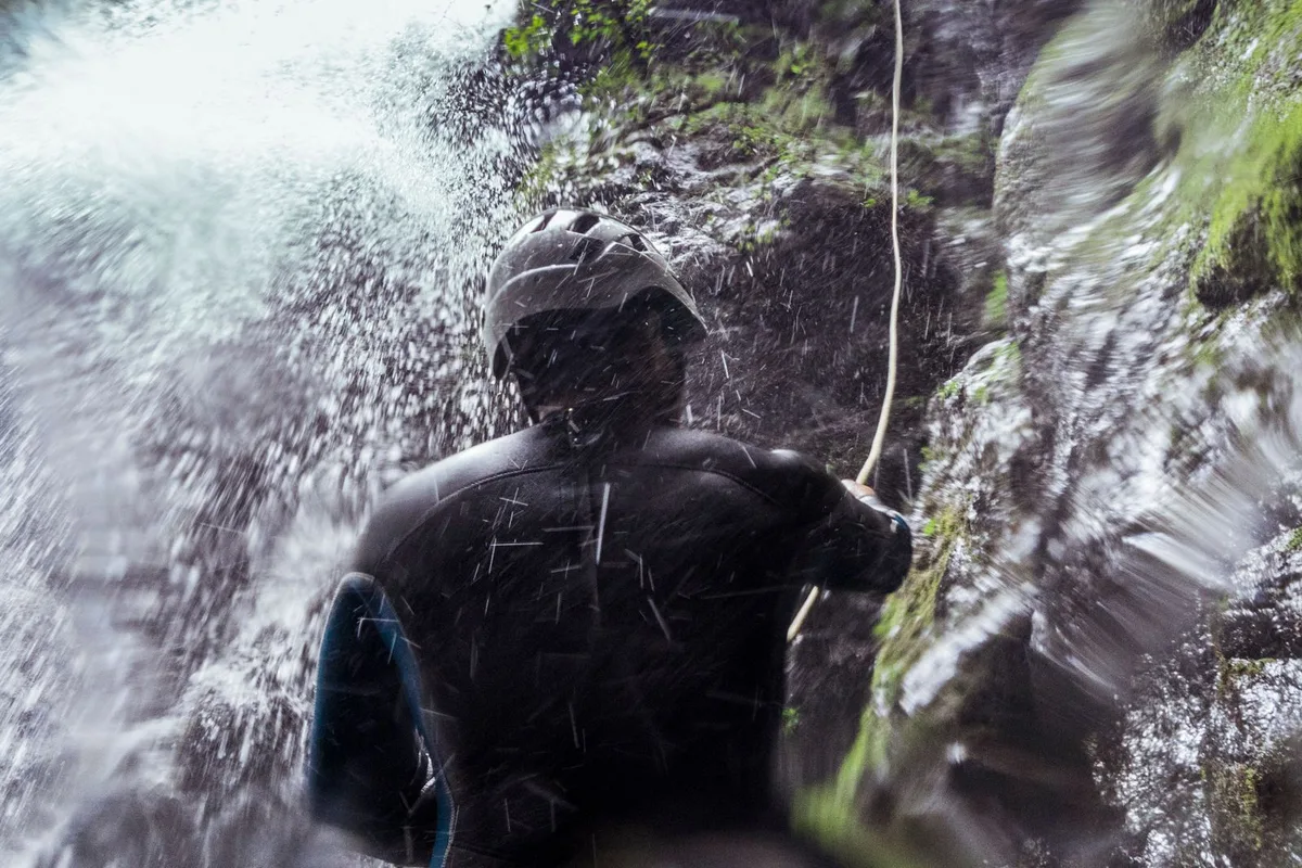 A canyoner rappelling through the spray of a waterfall