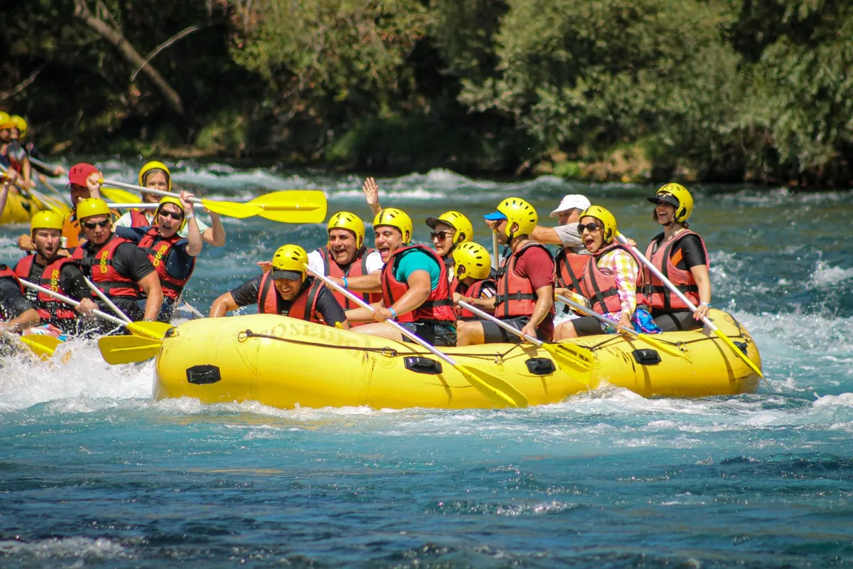 A raft crew in helmets paddling a green river