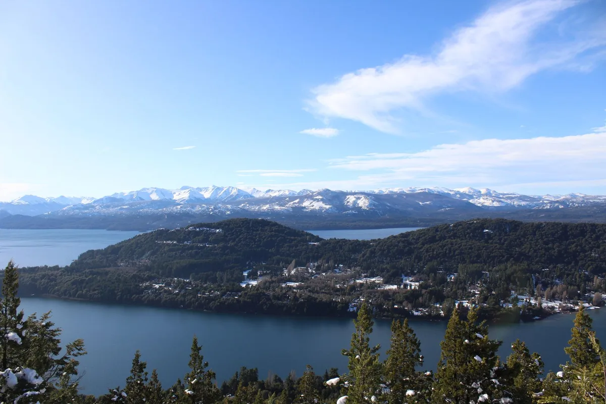 The lakes of Bariloche from above — forested peninsulas under the snowy Andes
