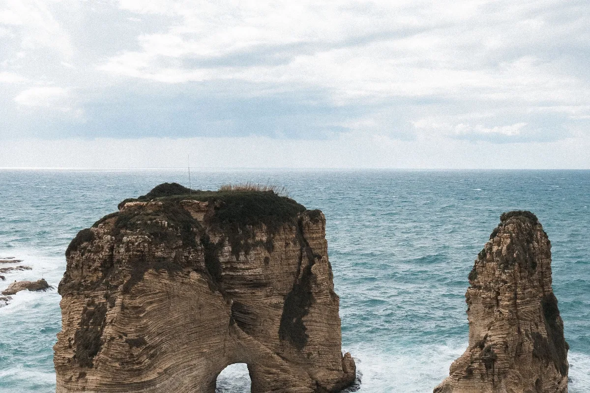 The Raouché Pigeon Rocks from above, waves breaking around the arch