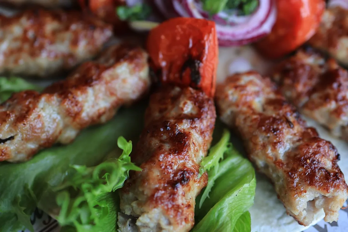 A plate of ćevapi with chopped onion, salad and flatbread