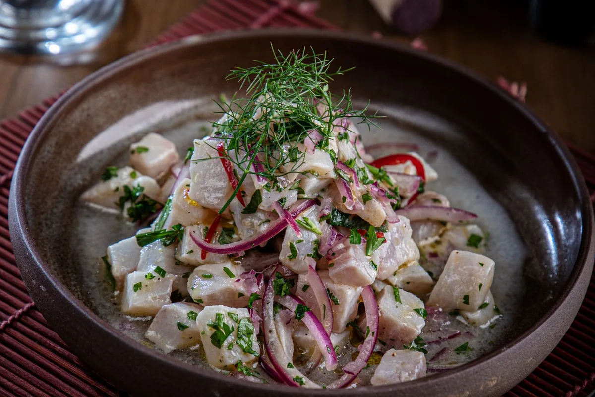 A bowl of seafood ceviche with red onion and herbs, the first order on the island