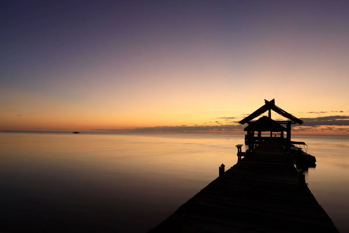 A dock reaching into a calm sunset sea off San Pedro