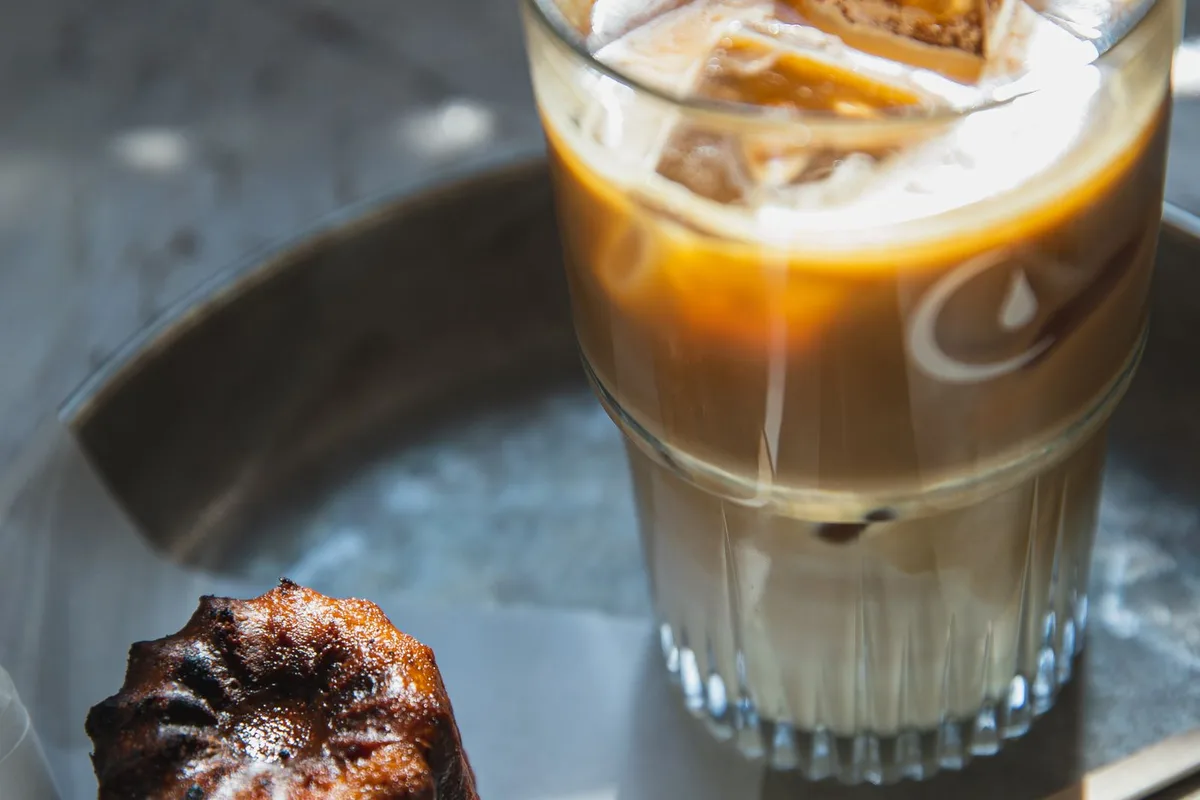 A canelé, Bordeaux's caramelised custard cake, beside an iced coffee