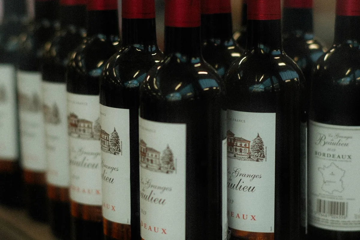 A row of Bordeaux red wine bottles, château labels facing out