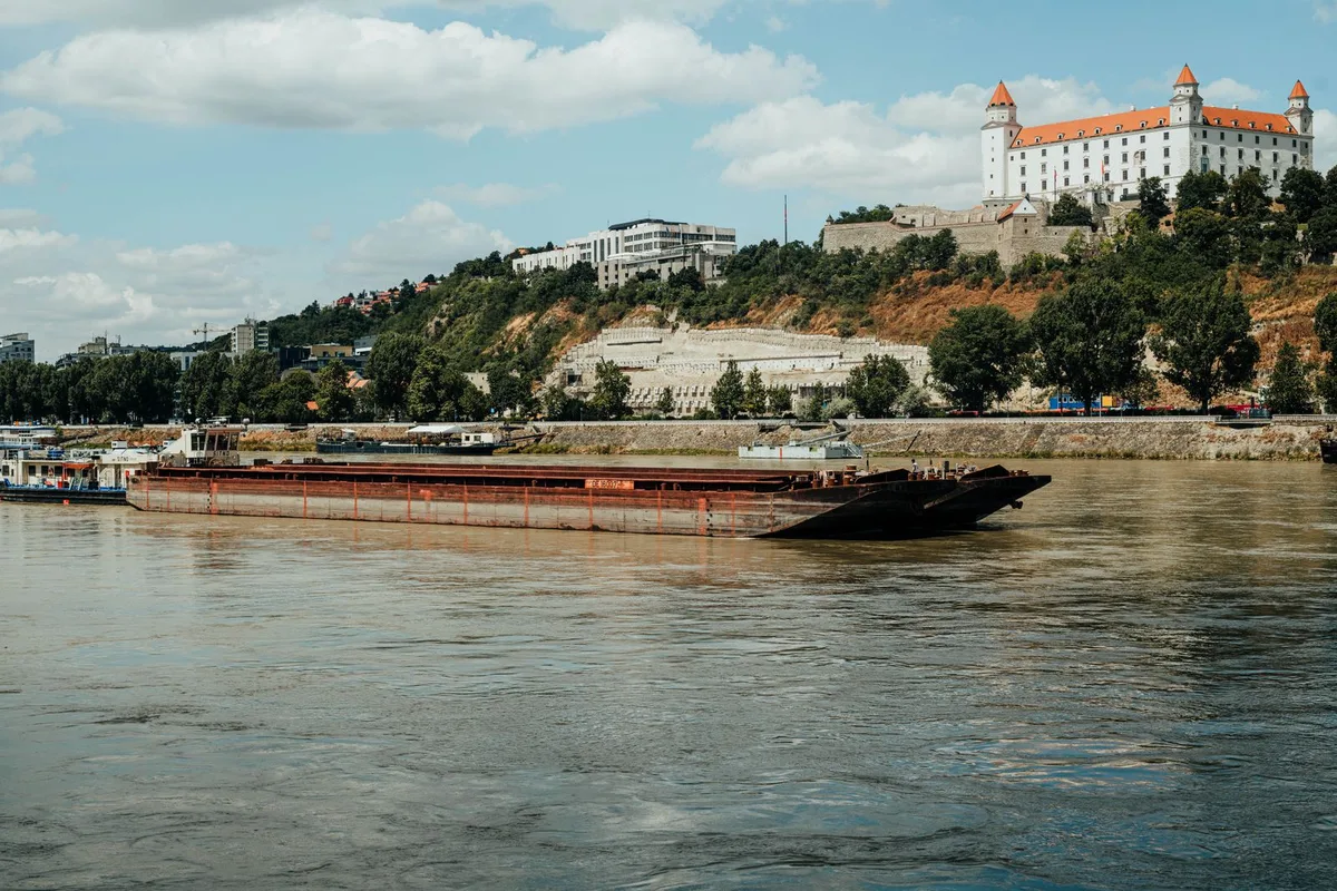 Bratislava Castle above the Danube, a cargo barge passing below the castle hill