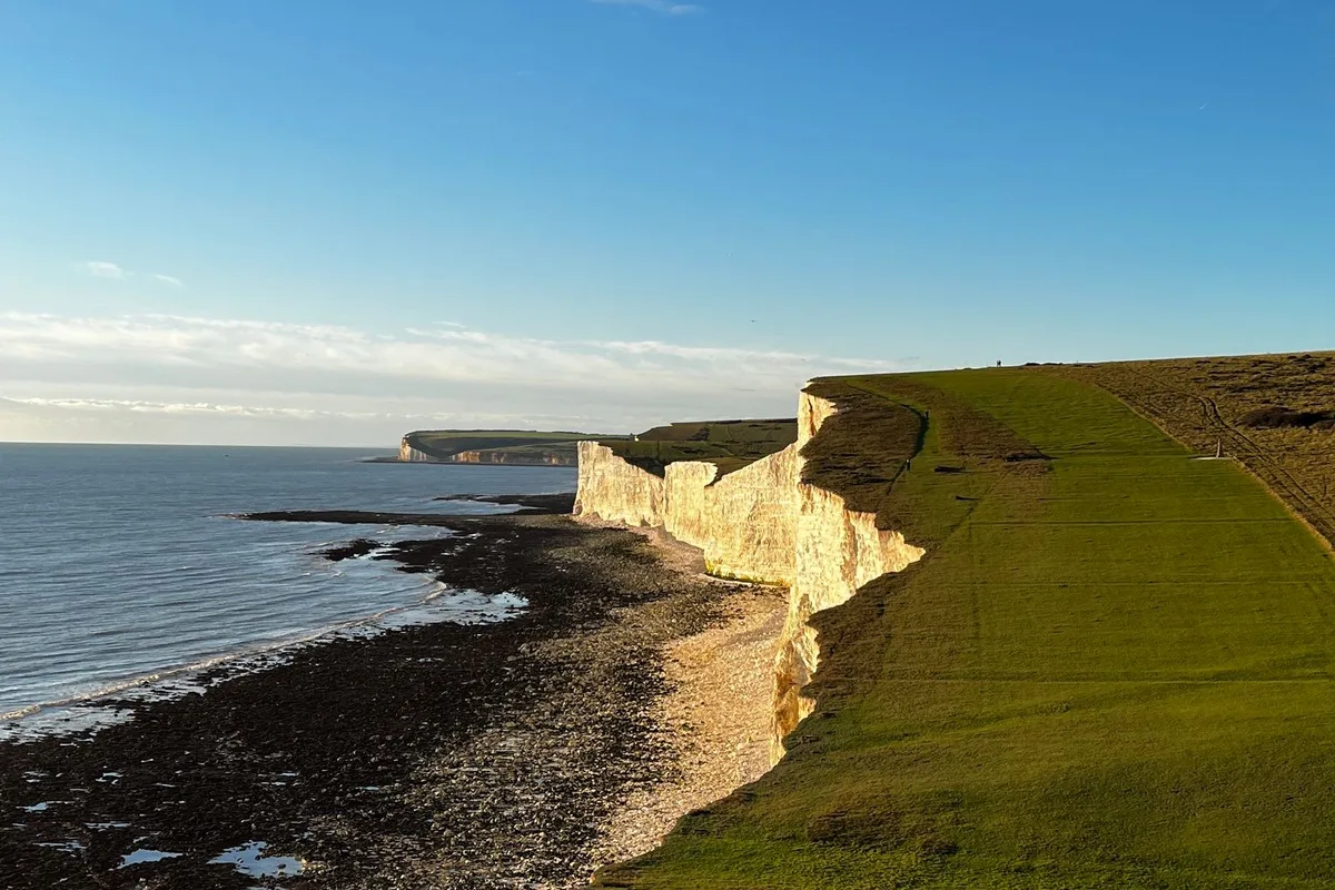 The Seven Sisters chalk cliffs above a rock-pool shore, east of Brighton in the South Downs