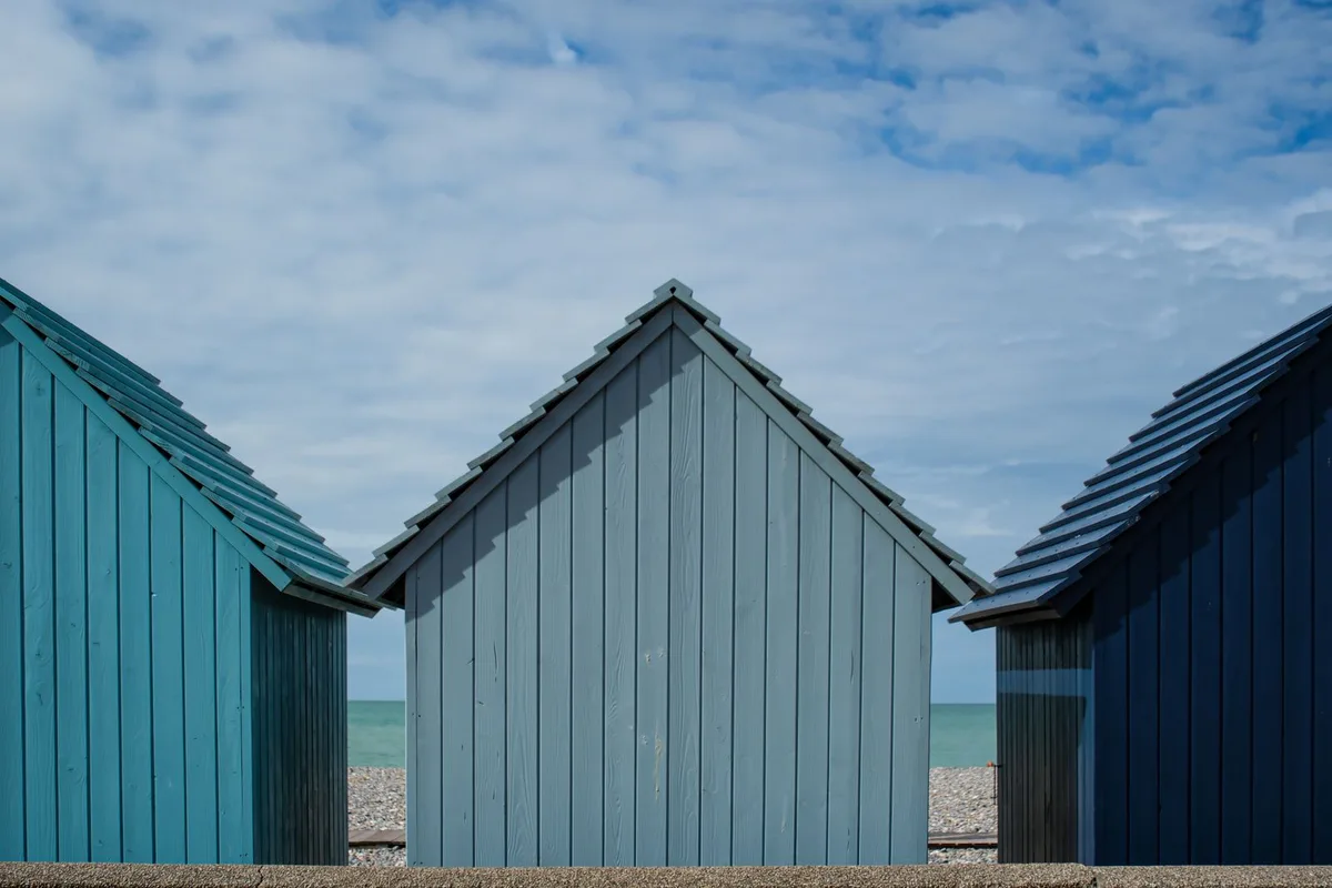 Pastel beach huts on the Hove seafront, facing the pebbles and the sea
