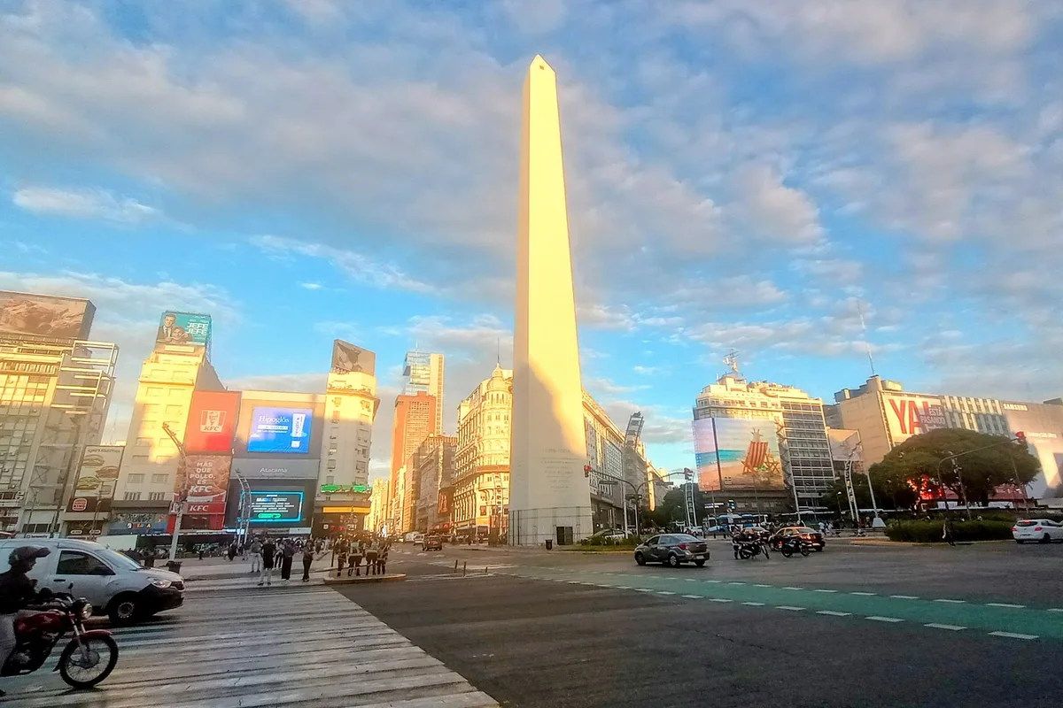 The Obelisco at golden hour, traffic streaming down Avenida 9 de Julio