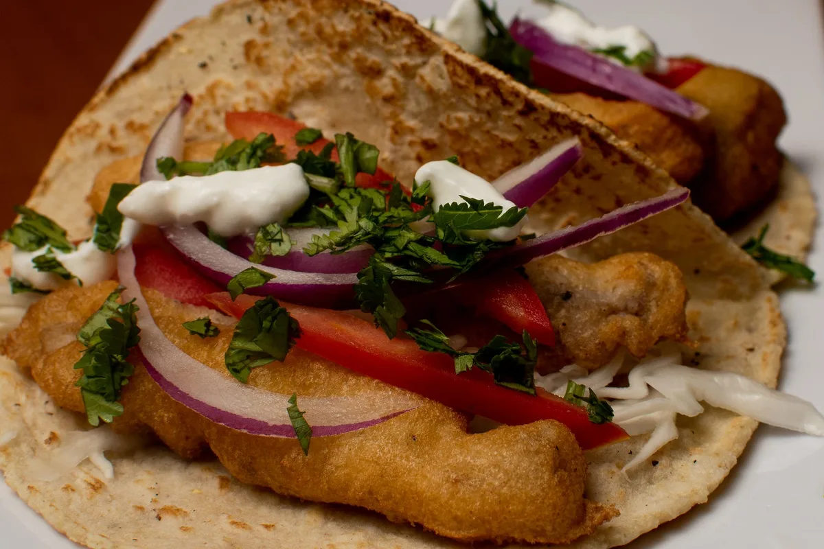Battered fish tacos with slaw, red onion and crema