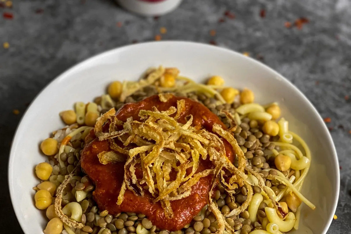 A bowl of koshary with chickpeas, fried onions and a glass of tea, Cairo