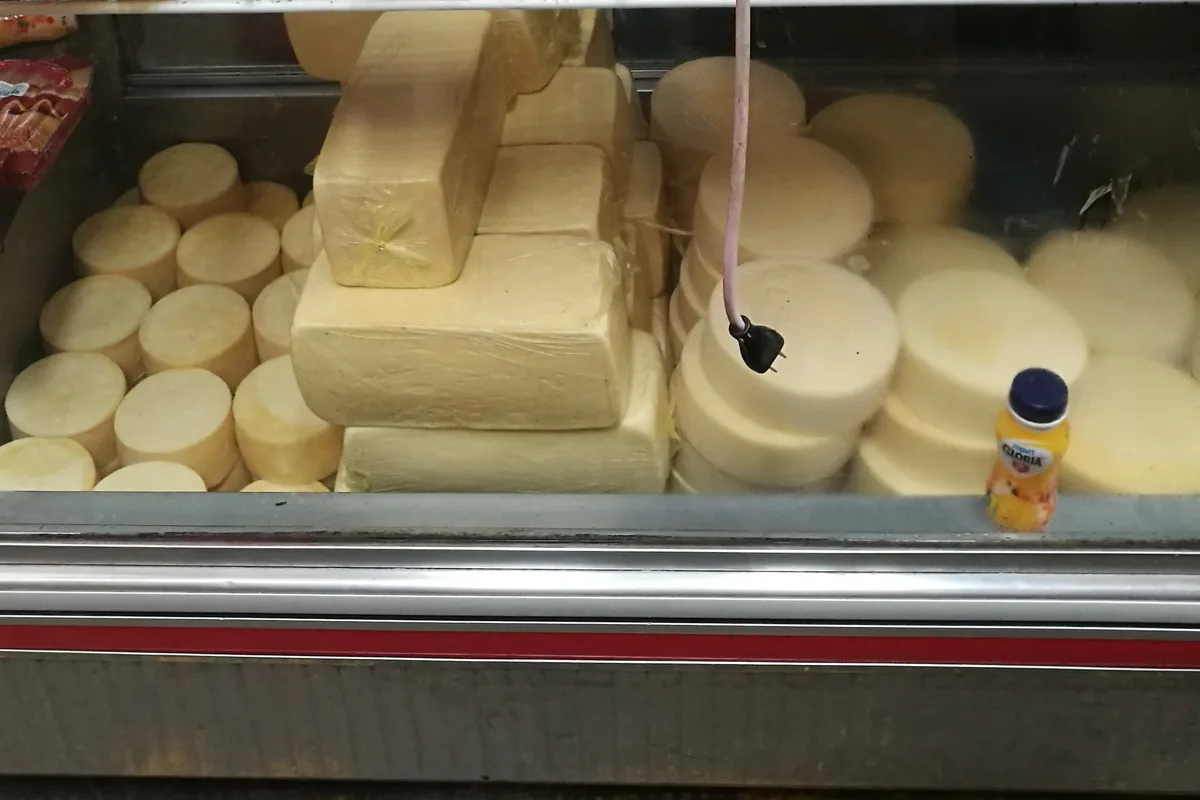 Cheese wheels and blocks stacked in a stall at Cajamarca's Mercado Central