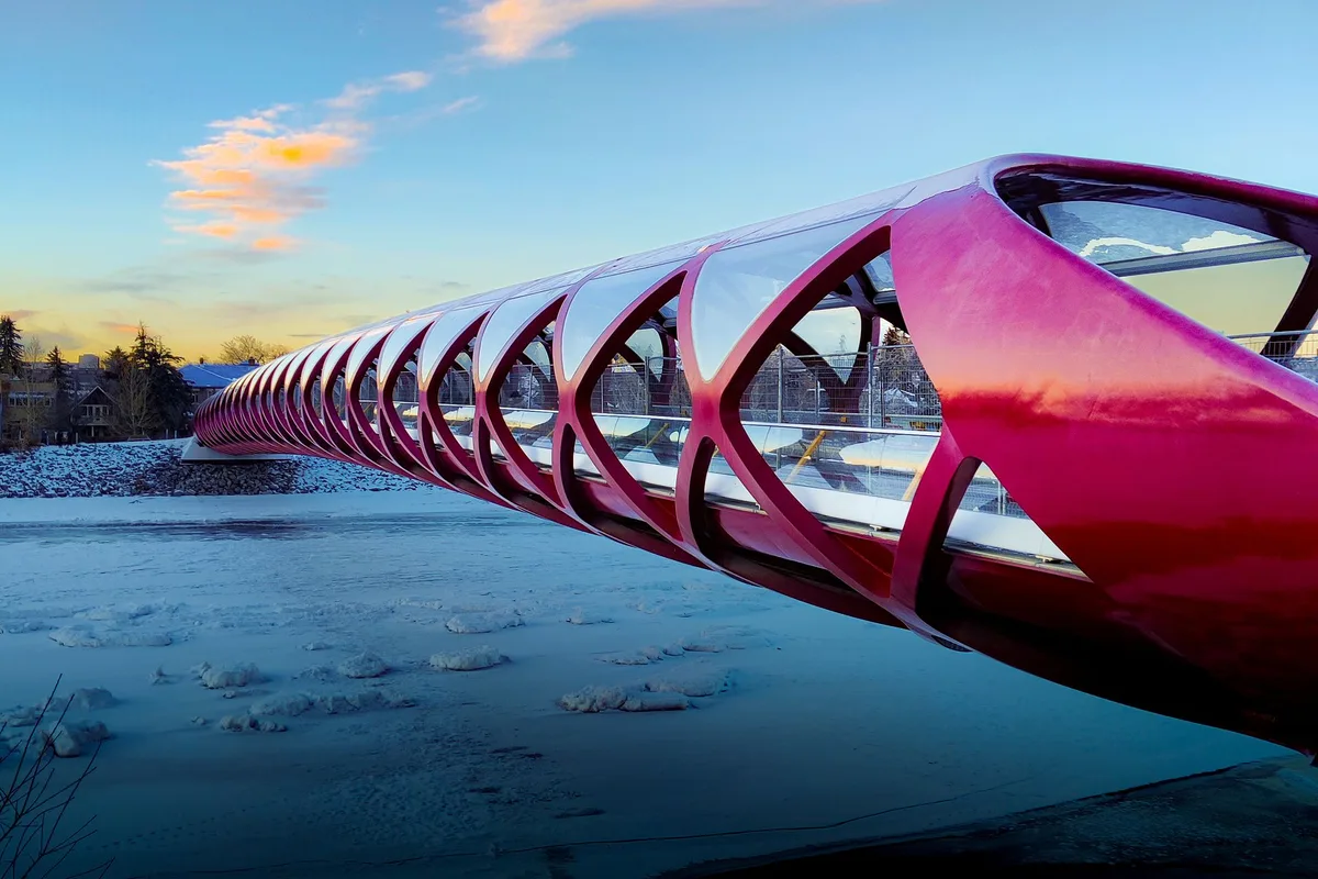 The red Peace Bridge crossing the Bow River in Calgary, the river frozen below