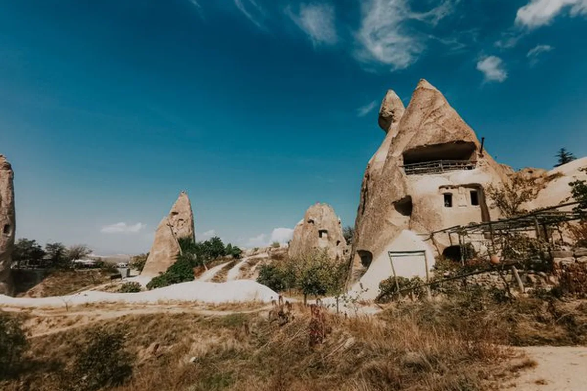 A fairy chimney in Göreme with a cave house carved into it, under a blue sky