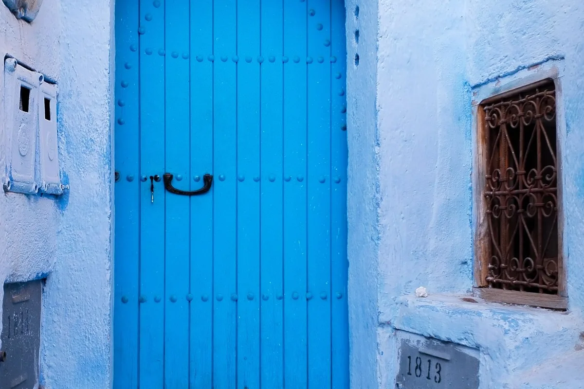 A blue arched doorway in a whitewashed Chefchaouen medina lane