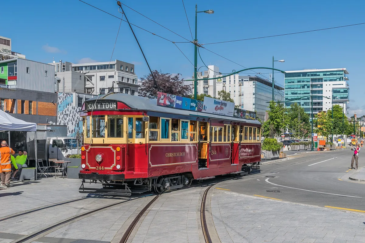 A red heritage tram turning through Cathedral Square in central Christchurch