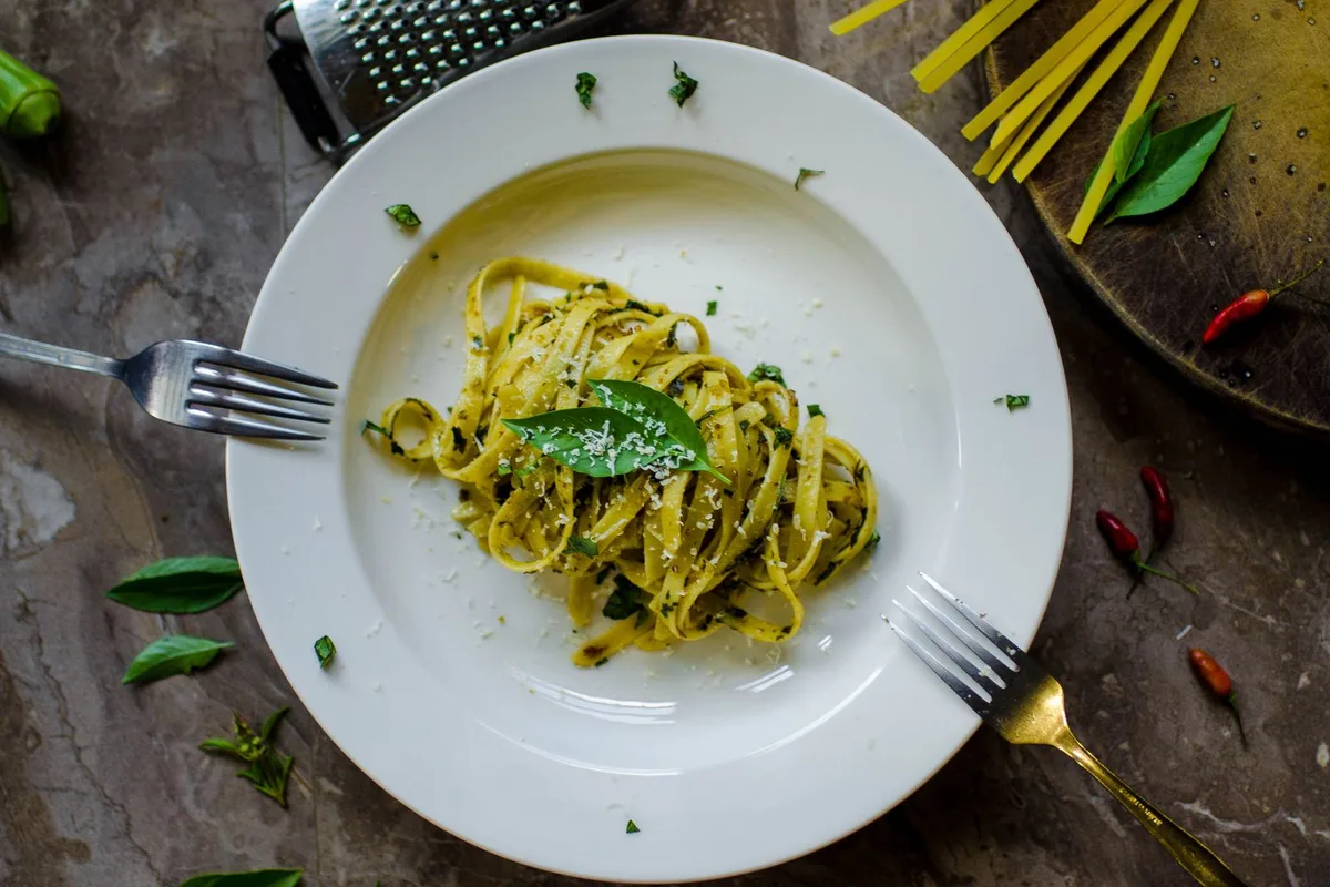 A plate of pasta with green pesto and basil, the sauce this coast invented
