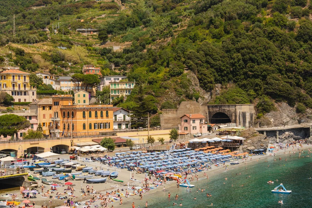 Monterosso's Fegina beach in high summer, umbrellas above the clear water