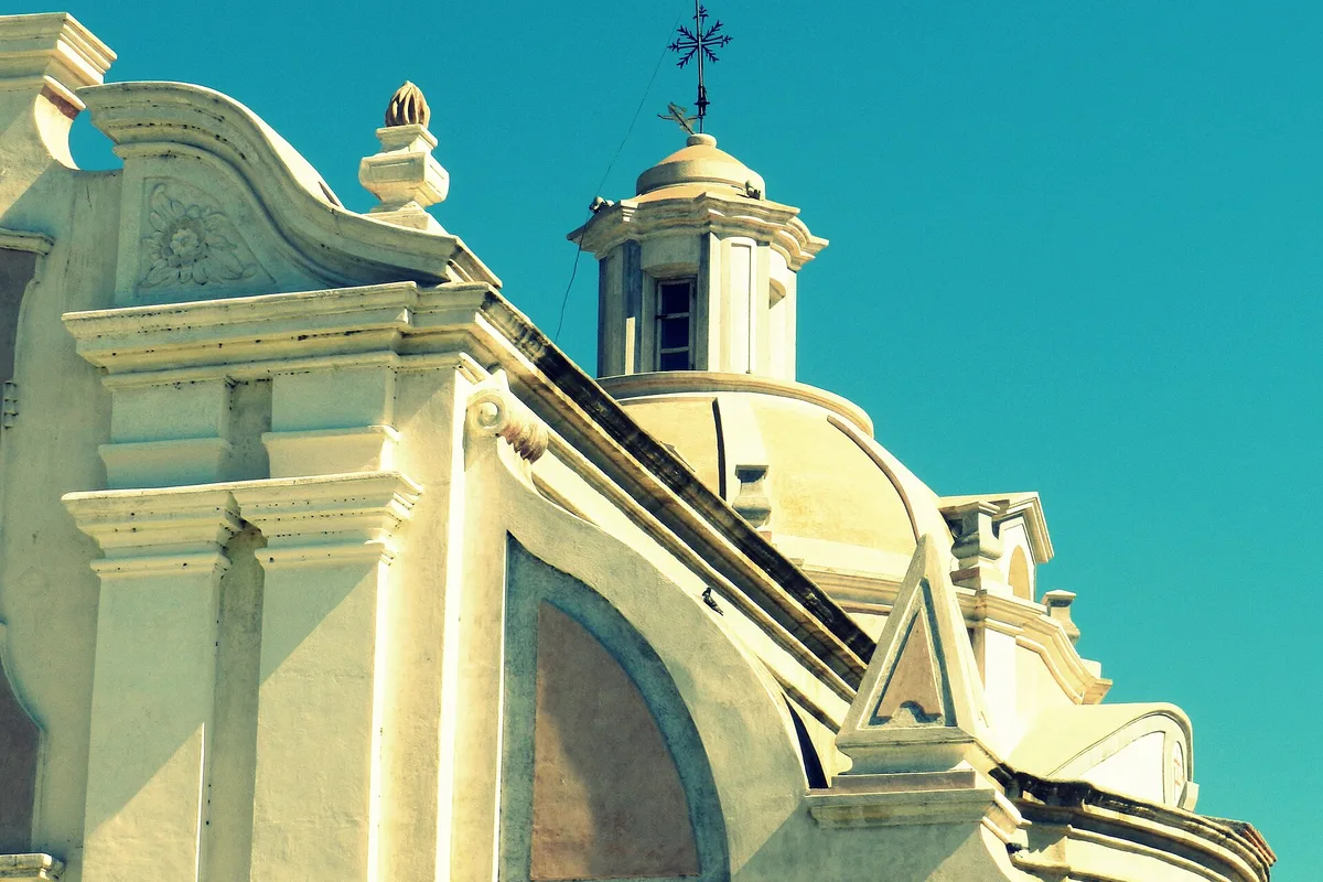 The baroque facade of the Jesuit Estancia church at Alta Gracia against a bright sky
