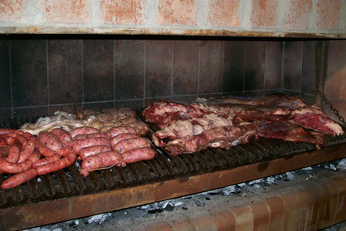 Beef and chorizos grilling over the coals of an Argentine parrilla
