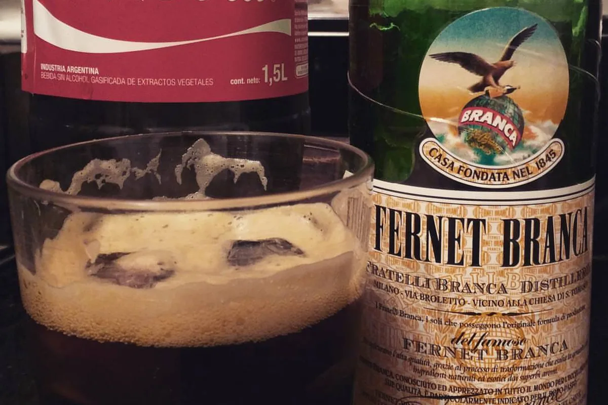 A glass of fernet con coca beside the Fernet Branca bottle and a Coke, Córdoba's signature pour