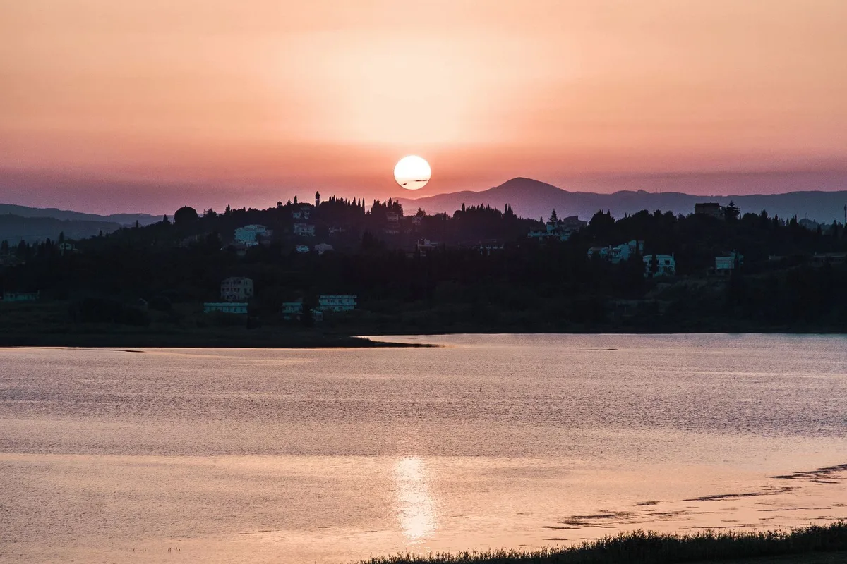 The sun setting over calm water on the evening cruise from Corfu Town