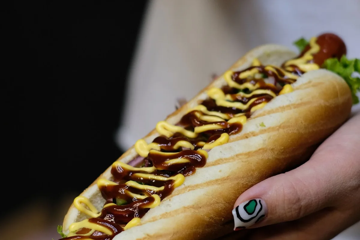 Chilli dogs with diced onion, held up at a Coney counter