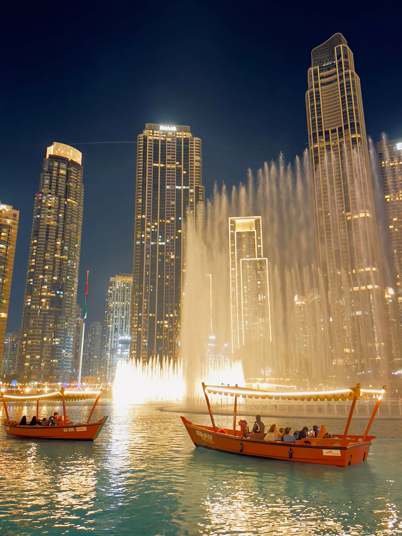Dubai Fountain show at night with abras on the water