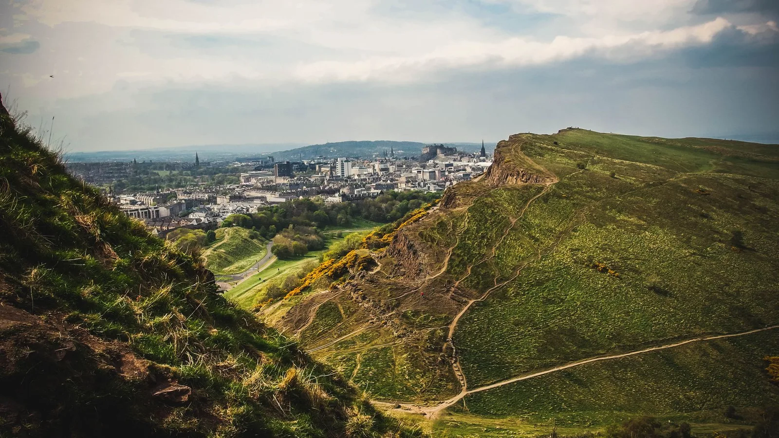 The paths over Salisbury Crags in Holyrood Park with Edinburgh Castle in the distance