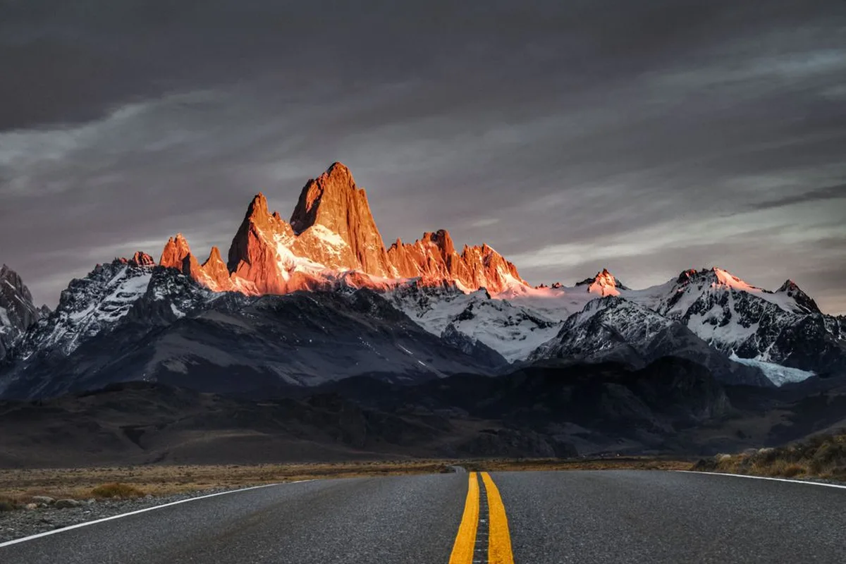 The road into El Chaltén running straight toward Fitz Roy, lit pink at dawn