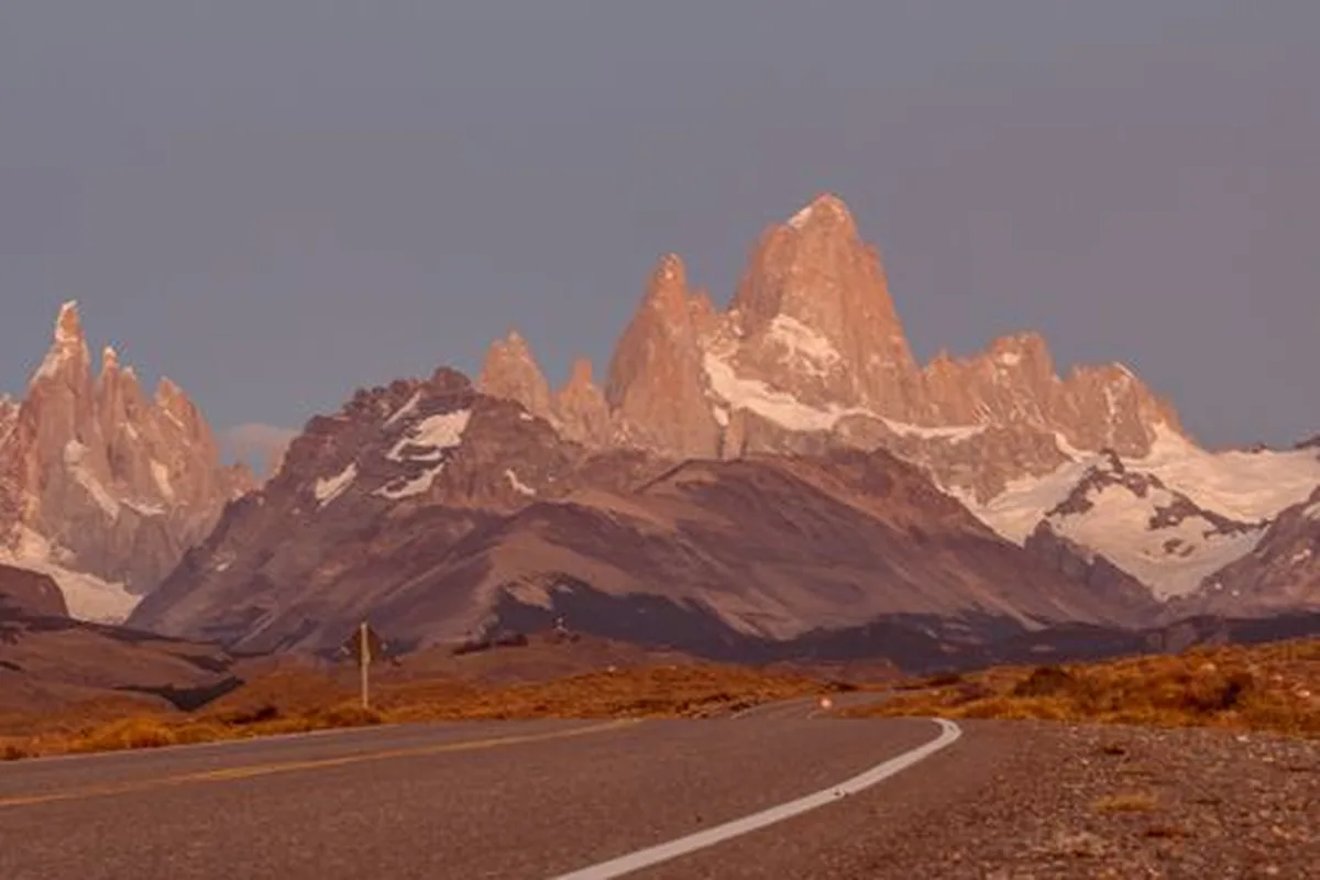 The road to El Chaltén at dusk, with Fitz Roy lit pink on the horizon