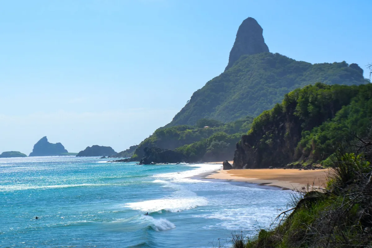 Praia da Conceição curving below the green cone of Morro do Pico