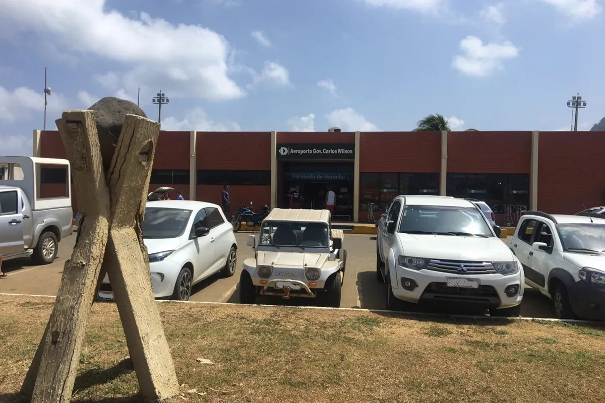 The small terminal building at Fernando de Noronha Airport, with buggies and cars outside
