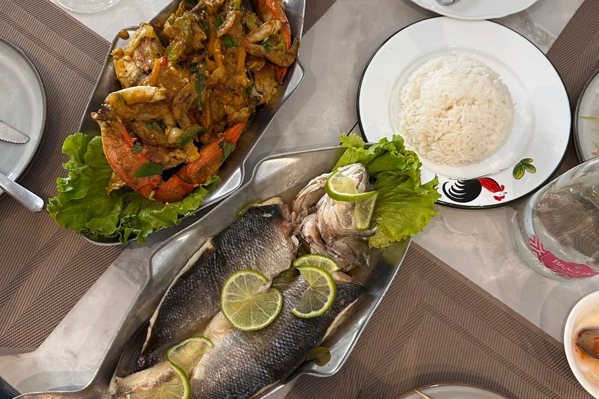 Whole grilled fish and seafood served on fish-shaped platters at an island table