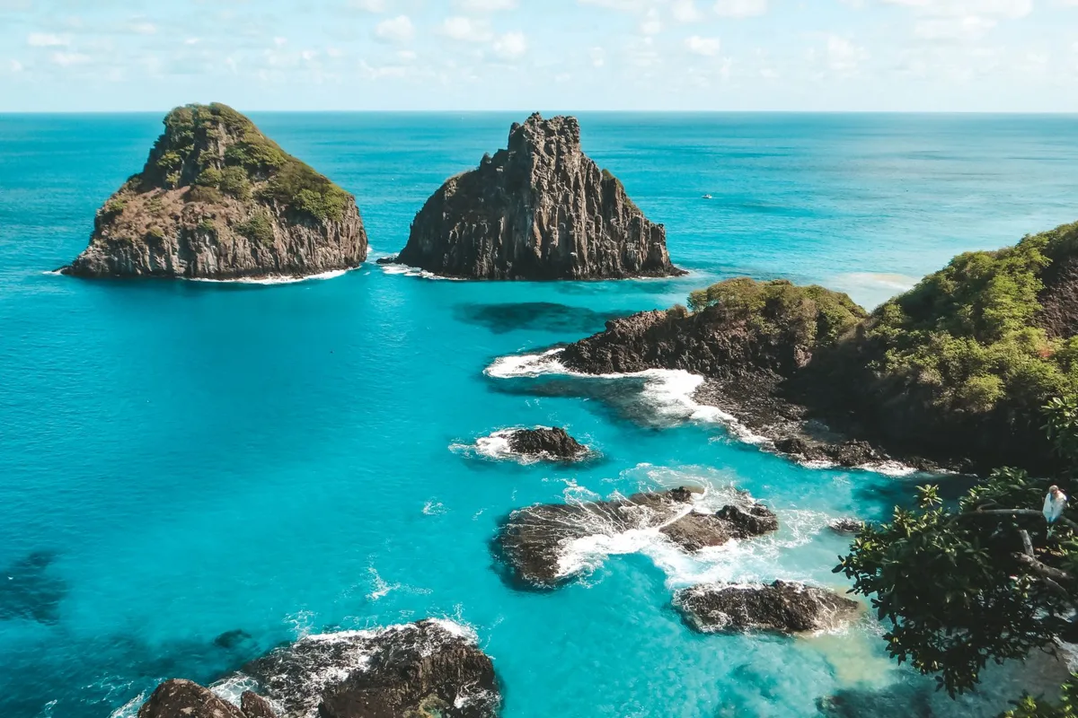 The Dois Irmãos rocks above the turquoise water of Baía dos Porcos