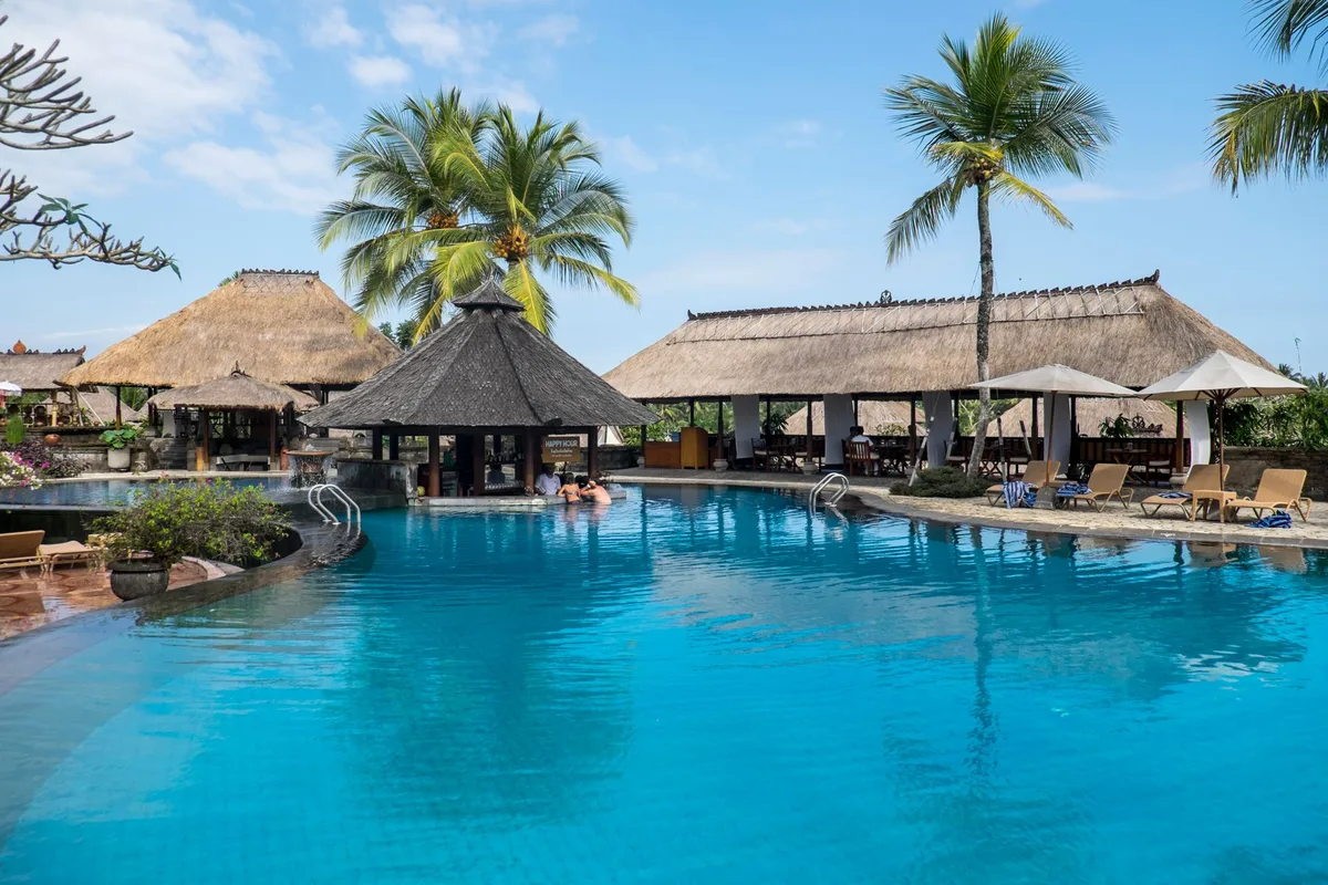 The pool at Malamala Beach Club, ringed by thatched shade and palms