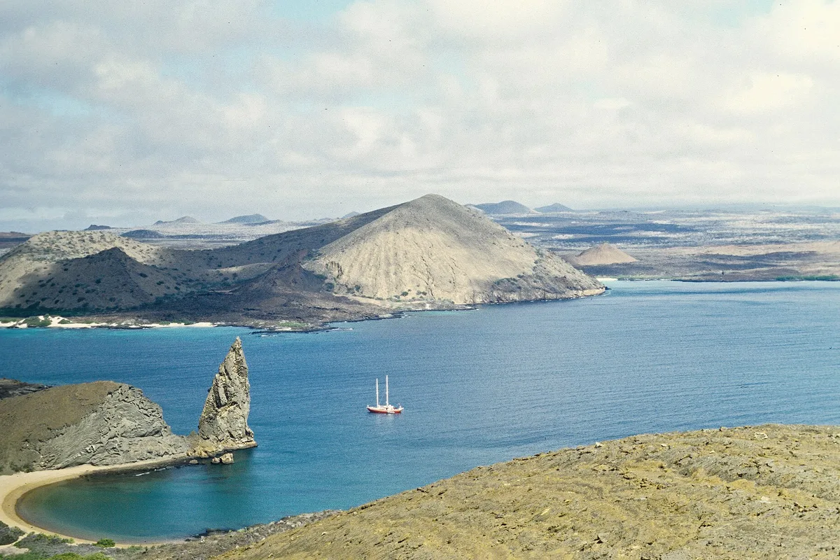 Bartolomé Bay and Pinnacle Rock from the island viewpoint, a yacht at anchor in the blue water