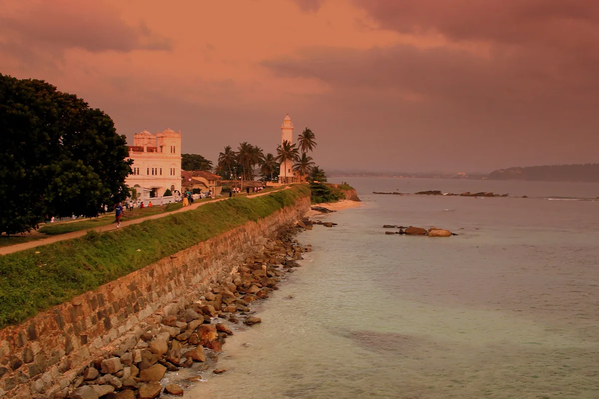 Galle Fort ramparts and the lighthouse at sunset above the sea