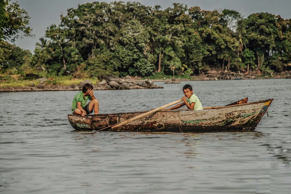 Two boys paddling a wooden boat on Lake Nicaragua near Granada